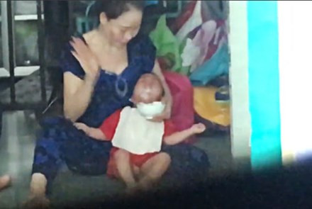 Bé trai bị kẹp đầu, liên tục bị đánh khi ăn. Ảnh cắt từ clip.