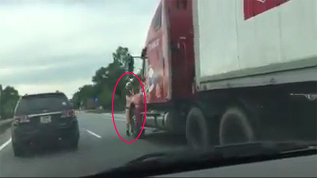 Chiến sĩ CSGT mắc kẹt trước mũi container bị kéo lê hàng trăm mét. (Ảnh cắt từ clip).