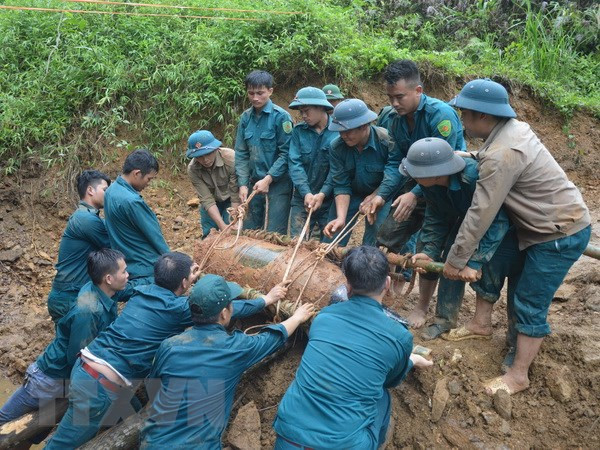 Chiến sỹ lực lượng vũ trang đưa bom xuống hố để hủy nổ. Ảnh: TTXVN phát.