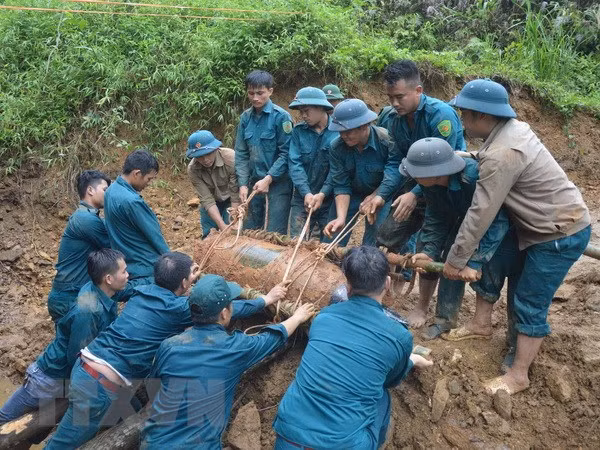 Chiến sỹ lực lượng vũ trang đưa bom xuống hố để hủy nổ. Ảnh: TTXVN phát.