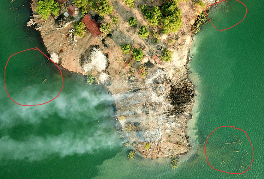 Từ trên cao nhìn xuống thấy rõ hàng loạt lóng gỗ (khoanh đỏ) nằm rải rác ven bờ sông, điểm tập kết gỗ cũng đã bị đốt cháy ngùn ngụt