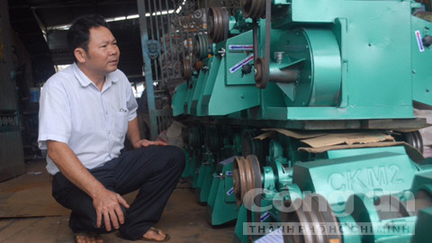 Nông dân Đặng Văn Bẩy bên Cơ sở Cơ khí Toàn Thắng do anh thành lập.