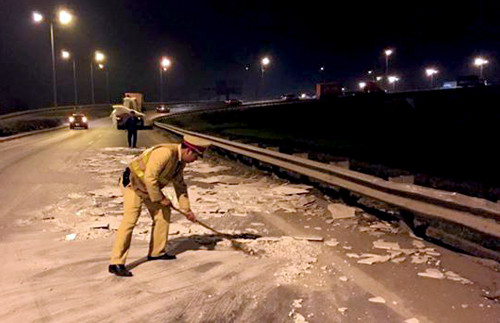 Tổ công tác cảnh sát giao thông, thay nhau đứng ra phân luồng và mượn chổi, xẻng quét dọn đá rơi vãi trong đêm.Ảnh: Nguyên Dân.