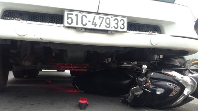 Chiếc xe máy bị cuốn vào gầm container, kéo lê trên đường.