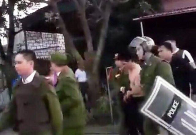 Đối tượng Đồng Thành Vinh (cởi trần) bị khống chế từ trong nhà đưa ra ngoài sau nhiều giờ cố thủ