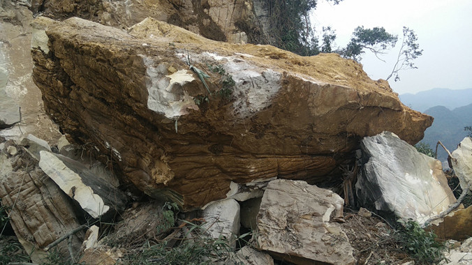 Phiến đá lớn hàng chục tấn này đè lên chiếc xe máy múc khiến nó nát, bẹp giúm.