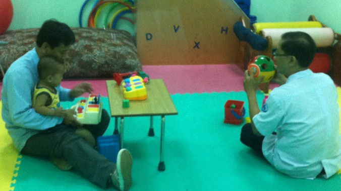 Bé Nguyễn Quốc Huy đang được ông Giao tập vật lý trị liệu với chân giả. Ảnh: Quốc Ngọc.