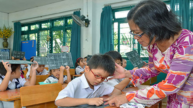 Cô giáo uốn nắn cho học trò từng nét chữ, nết người. Ảnh: Tấn Thạnh/Người Lao Động.