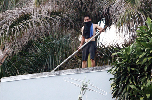 Nam thanh niên cố thủ trên nóc nhà nhiều giờ liền. Ảnh: Kh.Uyên