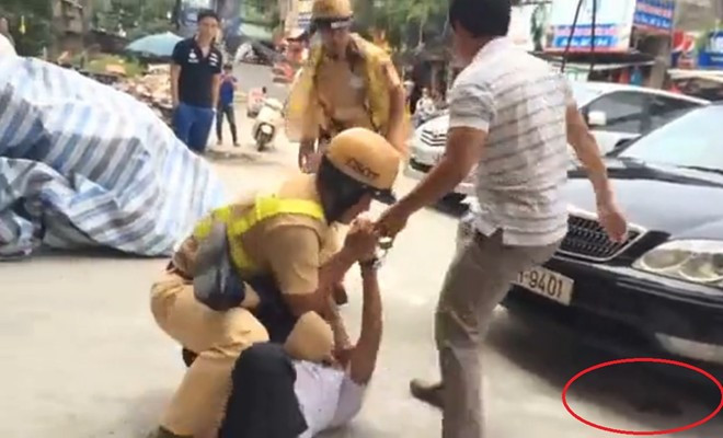 Súng của cảnh sát bị rơi (vùng khoanh đỏ) khi xô xát. Ảnh: Cắt từ clip