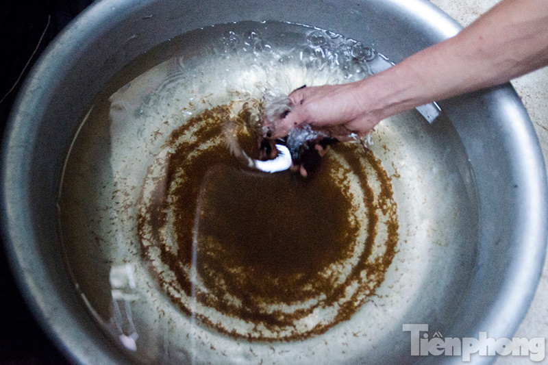 Nước chứa đầy cặn bẩn màu nâu sau tại một hộ gia đình trong thôn Tựu Liệt.