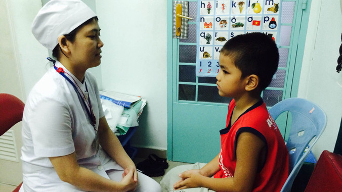 Bệnh nhi Trần V.T. đang được điều dưỡng Bùi Thị Duyên dạy cách phát âm. ảnh: L.N