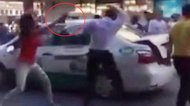 Cô gái cầm vật cứngi đập vào đầu tài xế taxi. Ảnh cắt từ clip