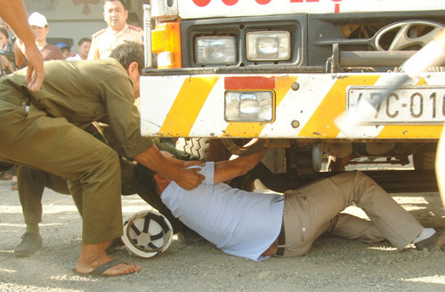 Tài xế chui xuống gầm xe cứu hộ, ngăn việc kéo xe vi phạm. Ảnh: Kh.Uyên