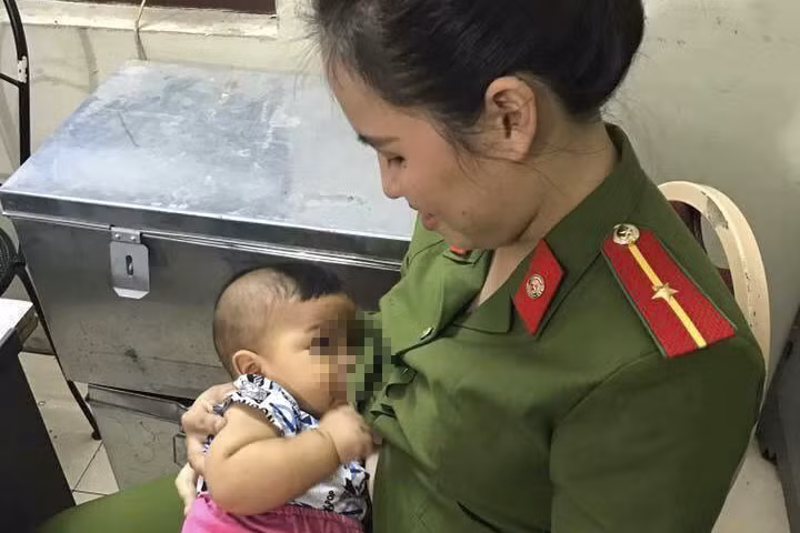 Bé trai đang được cán bộ công an phường chăm sóc.