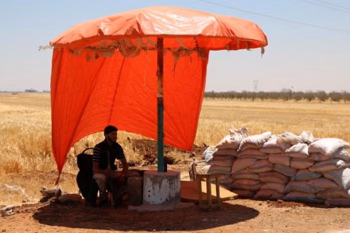 Một tay súng của nhóm Quân đội Syria Tự do ngồi nghỉ dưới bóng râm ở làng al-Nuaimah, thành phố Derra ngày 17/6. Ảnh: Reuters