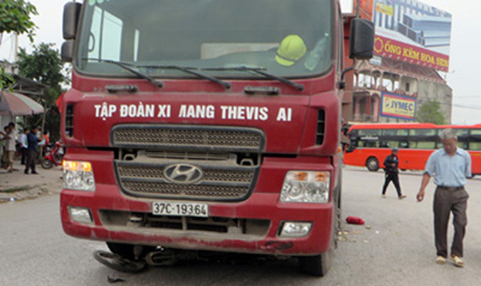 Xe đạp điện và người phụ nữ nằm dưới gầm xe tải.