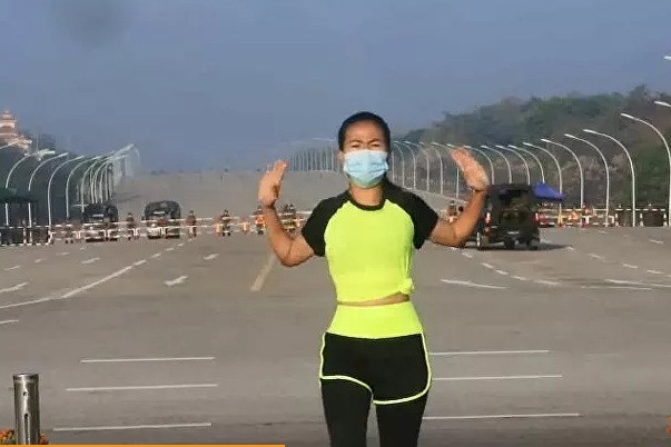 Người phụ nữ đang tập thể dục trước dàn xe quân sự