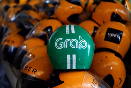 Mũ bảo hiểm đã sử dụng của tài xế Uber, Grab trong một cửa hàng ở Jakarta, Indonesia. Ảnh: Reuters.