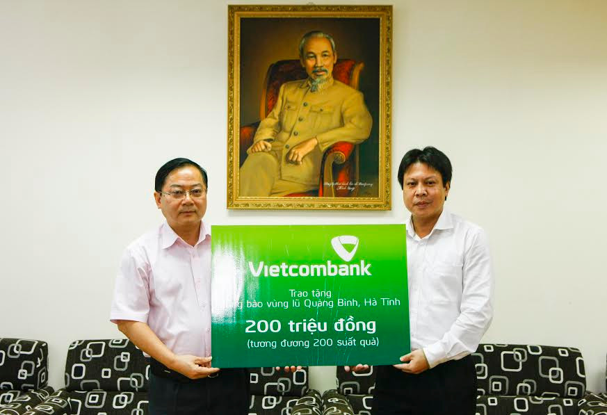 Đại diện Công đoàn Ngân hàng Vietcombank (bên phải) trao số tiền 200 triệu đồng đến bà con vùng lũ qua báo Tiền Phong. Ảnh: Như Ý 