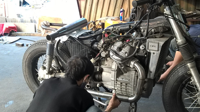 Thợ độ xe đang độ thay thế pô ống xả bằng hợp kim cho một chiếc xe độ phân khối lớn.
