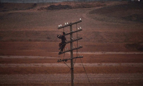 Một công nhân Triều Tiên đang sửa đường điện nằm dọc theo tuyến đường sắt nối từ Bình Nhưỡng tới tỉnh Bắc Pyongan hồi năm 2012. Ảnh: AFP.