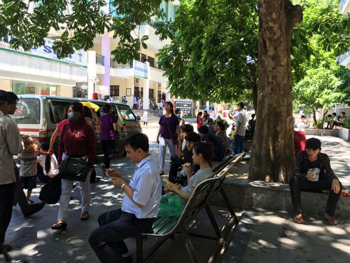 Người nhà bệnh nhân tránh nắng tại Bệnh viện Bạch Mai. Ảnh: Diệu Linh 