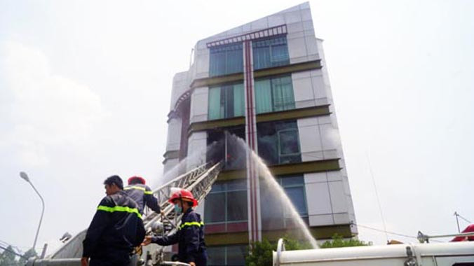 Cảnh sát chữa cháy dùng xe thang dập đám cháy. Ảnh: Nguyệt Triều.