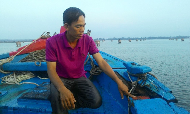 Ông Nguyễn Thương và vết nứt bên mạn tàu do bị đâm. Ảnh: N.Tiến.