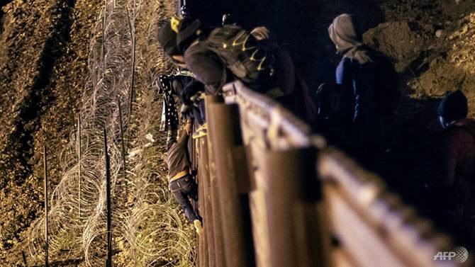 Một em bé từ Trung Mỹ đang vượt qua hàng rào ở biên giới Mỹ - Mexico để vào Mỹ hôm 1/1/2019/ (Ảnh: Guillermo Arias)