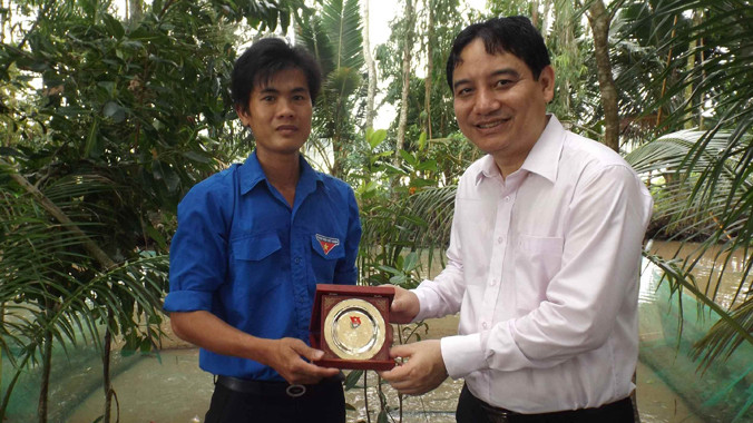 Anh Nguyễn Đắc Vinh (bên phải) tặng biểu trưng cho anh Nguyễn Văn Khoa. Ảnh: Hòa Hội.