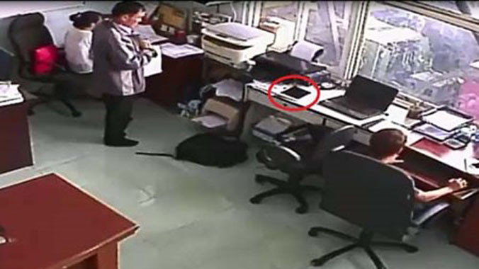 Tên trộm đang tăm tia chiếc iPad để trên bàn (ảnh cắt từ clip).