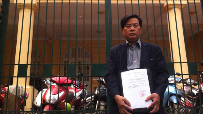 Ông Bình với tờ giấy mời đến dự buổi xin lỗi, trước cổng TAND Hà Nội sáng 2/4