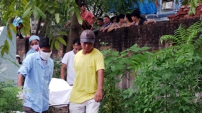 Lực lượng chức năng đưa thi thể nạn nhân ra khỏi nghĩa trang.