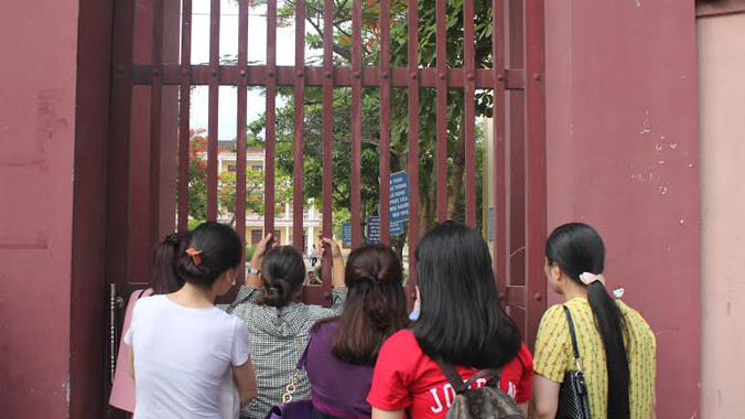 Các phụ huynh đưa con đi dự thi mặc cho trời nắng nóng vẫn lo lắng theo dõi phía ngoài tường bao khu vực thi.