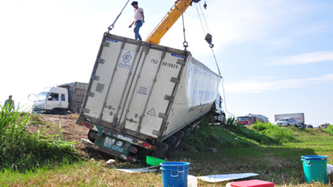 Các phương tiện cứu hộ đang cẩu xe container lật nghiêng dưới ruộng lên quốc lộ. Ảnh: Trí Tín/ VnExpress