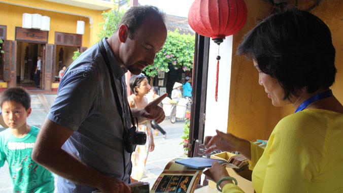 Du khách nước ngoài vui vẻ mua vé sau khi được tư vấn đầy đủ thông tin. Ảnh: H.Văn