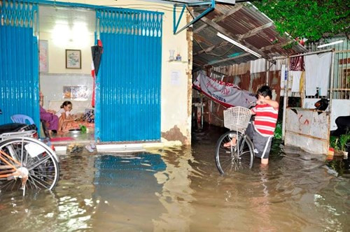 Người dân bất lực nhìn nước ngập tràn vào nhà. Ảnh: Ngô Bình