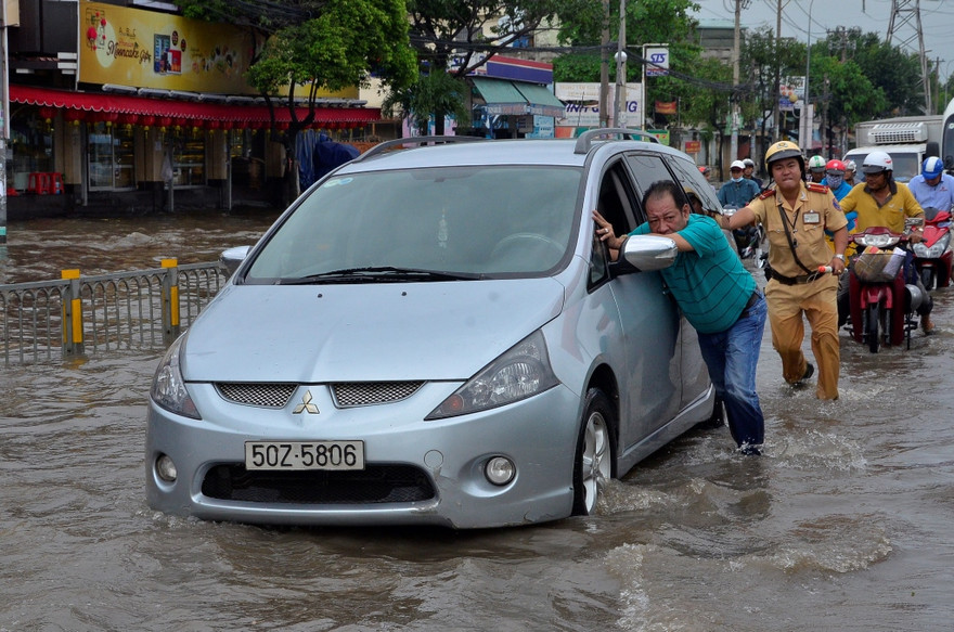 Một CSGT dầm mình trong nước nỗ lực đẩy chiếc xe ô tô bị chết máy.