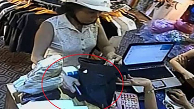 Cầm lấy túi đựng quần áo nhân viên đưa cho, nữ hành khách cố tình che chiếc iPhone 5 của nhân viên để giữa bàn.