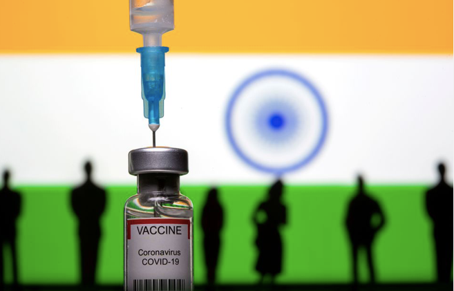 Một đồ chơi hình lọ vắc-xin và mũi tiêm được chụp trước quốc kỳ Ấn Độ. (Ảnh: Reuters)