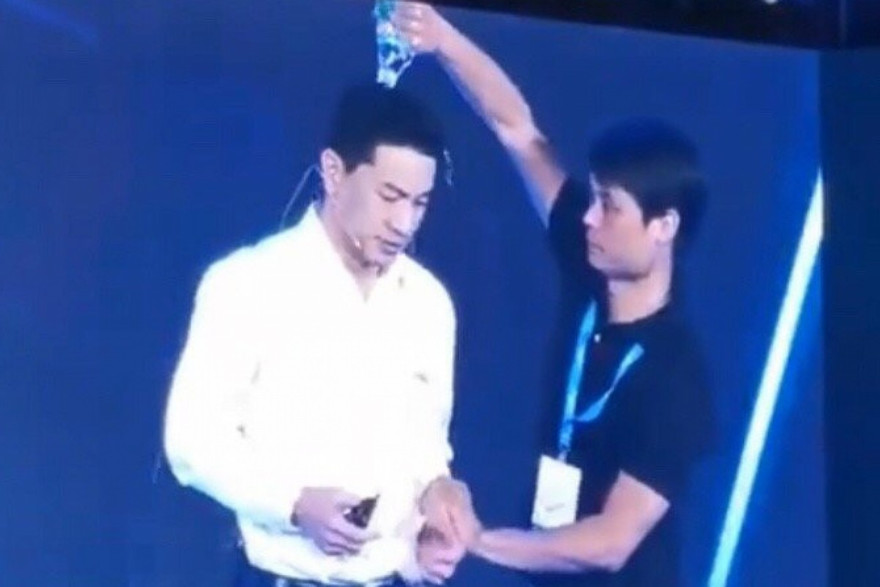 Ông Robin Li Yanhong bị người mặc áo đen đổ chai nước xuống đầu. (Ảnh: SCMP)