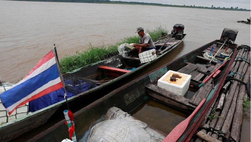 Một ngư dân Thái Lan đang múc nước khỏi thuyền đánh cá. (Ảnh: Reuters)