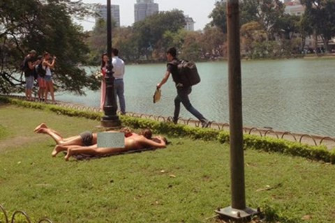 Hai nữ du khách mặc bikini tắm nắng bên Hồ Gươm