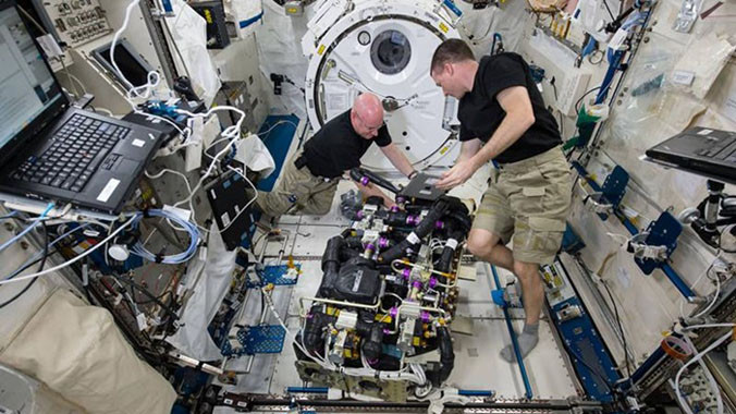 Phi hành gia Kelly (trái) và Watts (phải) đang loại bỏ carbon dioxide trong một thiết bị.