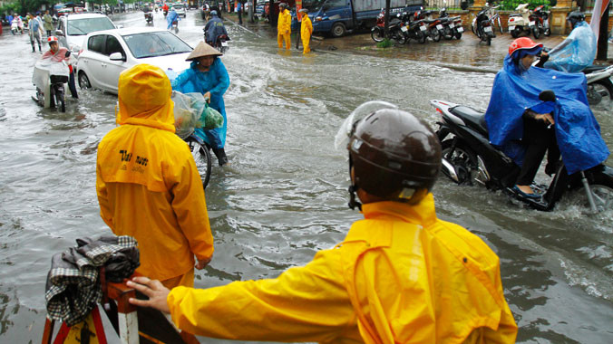  Công nhân cấp thoát nước Hà Nội đứng túc trực tại điểm ngập trên đường Lê Trọng Tấn. ảnh: Như Ý