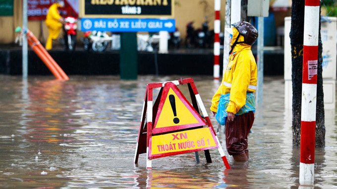 Công nhân thoát nước đội mưa giúp người đi đường. Ảnh TT0