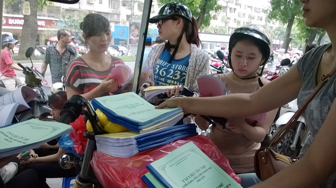 Thí sinh mua tài liệu ôn tập thi vào ngành thuế các năm trước do các trung tâm luyện thi bày bán công khai trước cổng trụ sở Cục Thuế Hà Nội. Ảnh: Quỳnh Nga 