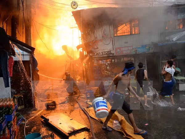 Nhân viên cứu hỏa và người dân địa phương nỗ lực khống chế đám cháy dữ dội tại một khu dân cư nghèo ở khu vực ngoại ô thủ đô Manila. (Ảnh: AFP/TTXVN)