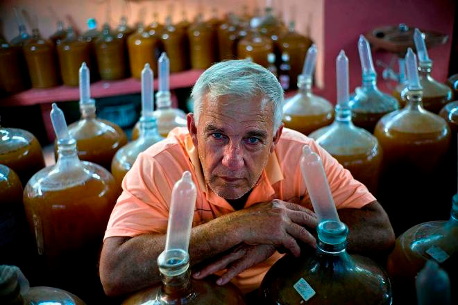 Ông Orestes Estevez bên những bình rượu nho đội bao cao su. ảnh: Ramon Espinosa
